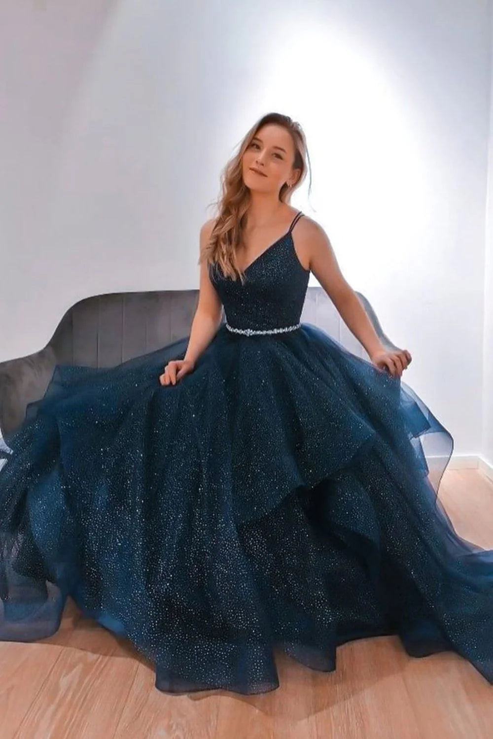A sparkling blue V-neck with a deep blue belt and a long, fluffy blue formal evening dress for a ball
